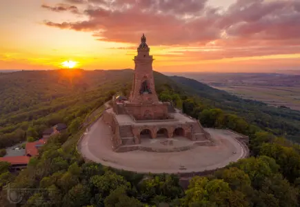 Riesiges Denkmal mit Turm und untergehender Sonne auf einem Berg