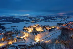 Beleuchtetes Schloss bei Nacht im Schnee