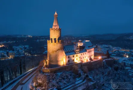 Beleuchtete Burg mit Bergfried in der Dunkelheit