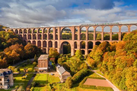 Eisenbahnbrücke mit Zug im bunten Herbstwald