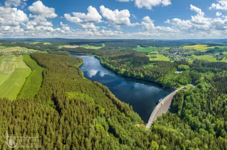 Stausee mit Staumauer in grüner Landschaft