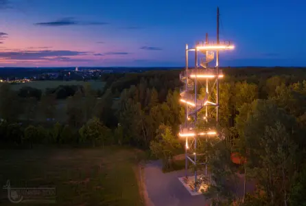 Beleuchteter Aussichtsturm in nächtlicher Landschaft