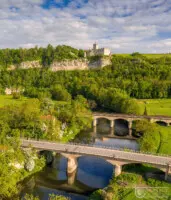 Zwei Brücken über einem Fluss vor einer Burgruine