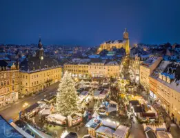 Beleuchtete Stadt mit Kirche und Weihnachtsmarkt bei Nacht im Schnee