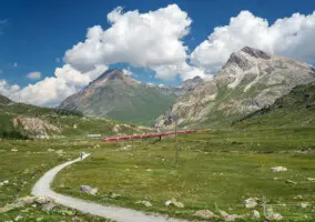 Rote Eisenbahn im Hochgebirge mit plastischen Wolken