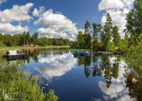 See Härsjö mit spiegelnden Bäumen und Wolken