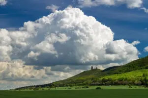 Große Wolke über grüner Landschaft mit Burgruine